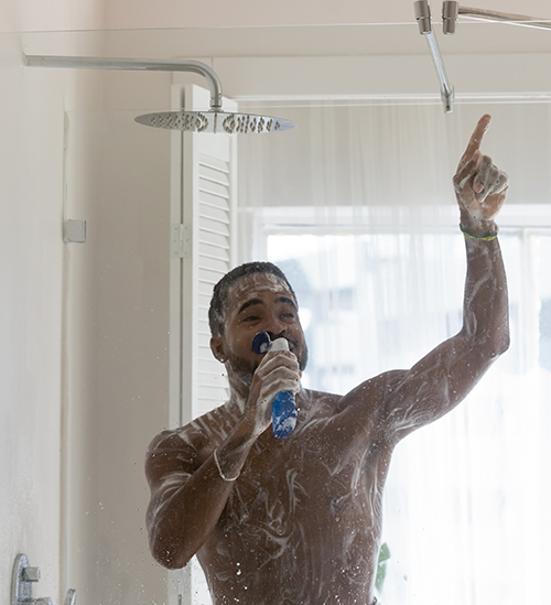 Positive African American man having fun in bathroom, singing